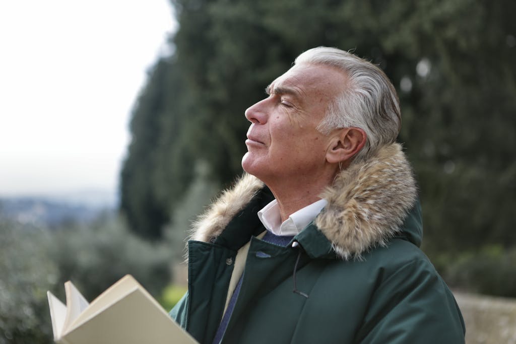 Senior man with white hair, eyes closed enjoying fresh air in Tuscany's natural setting. Cold & Flu DUO